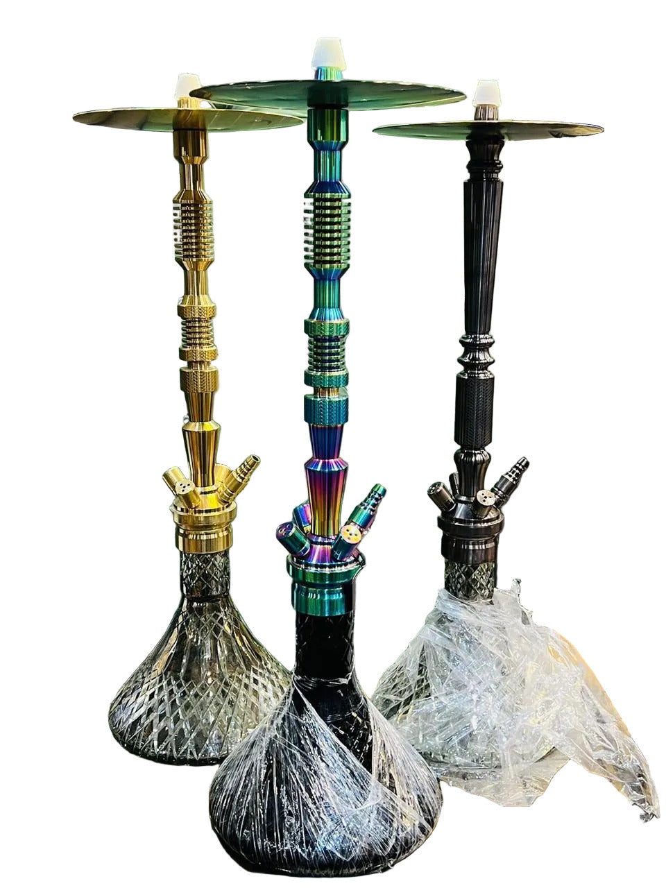 Three hookahs on a table with a green tufted headboard in the background.